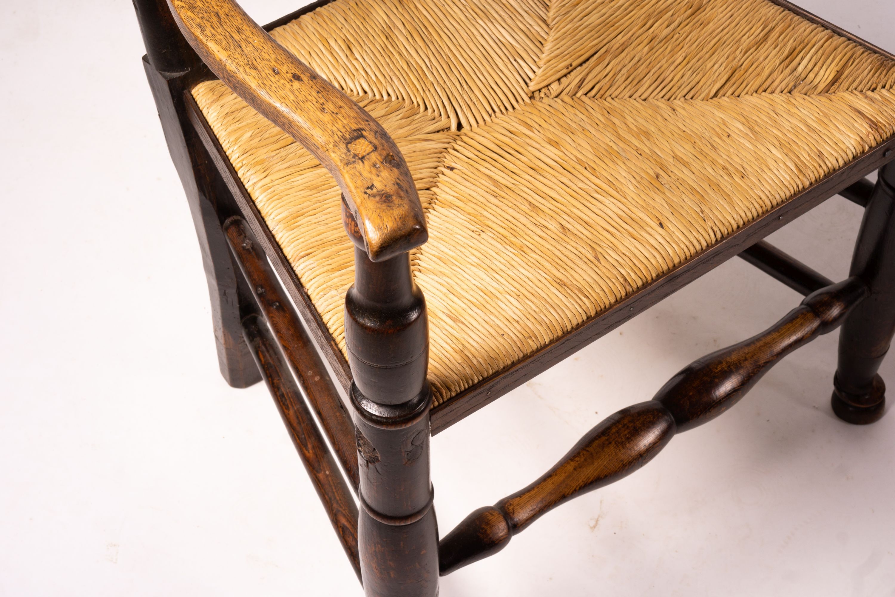 A pair of early 19th century Lancashire ash and fruitwood rush seat ladderback elbow chairs, width 60cm, depth 46cm, height 110cm